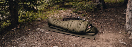 Man wild camping, laying in sleeping bag.