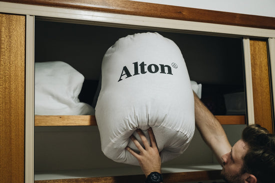 Man stores a sleeping bag in a cupboard.