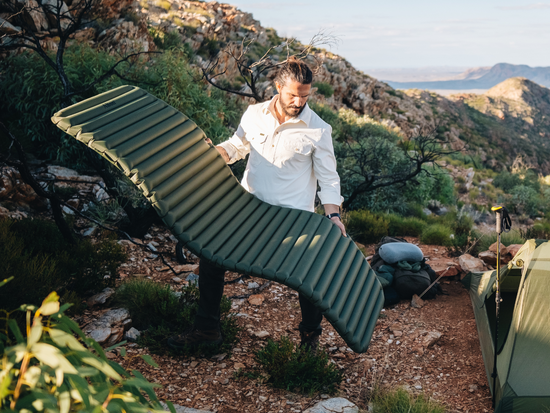 Man holds up insulated sleeping mat.