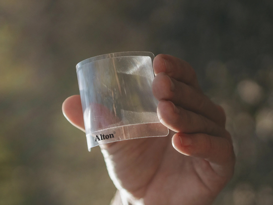 Close up of Fresnel lens for bushcraft being bent to show it is flexible.
