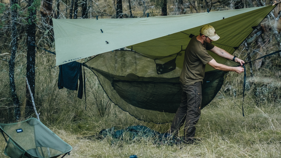 Man setting up camping hammock with 3mx3m ultralight tarp for protection