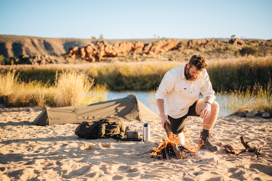 Man lighting a camp fire wearing Alton's hiking apparel