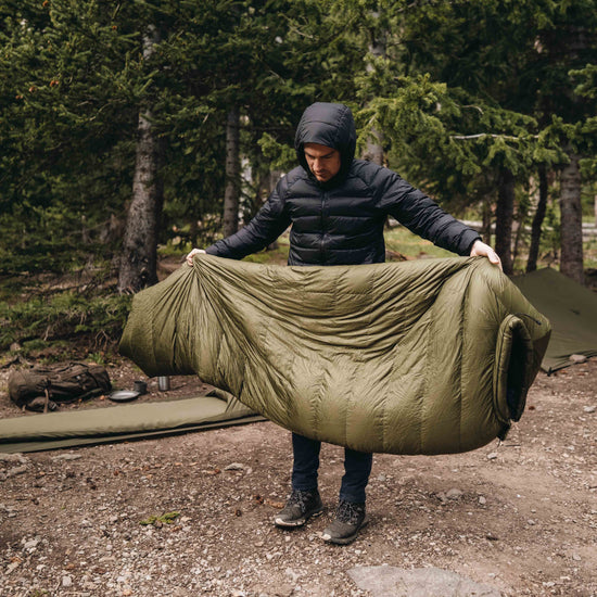 Man fluffs up down sleeping bag. 